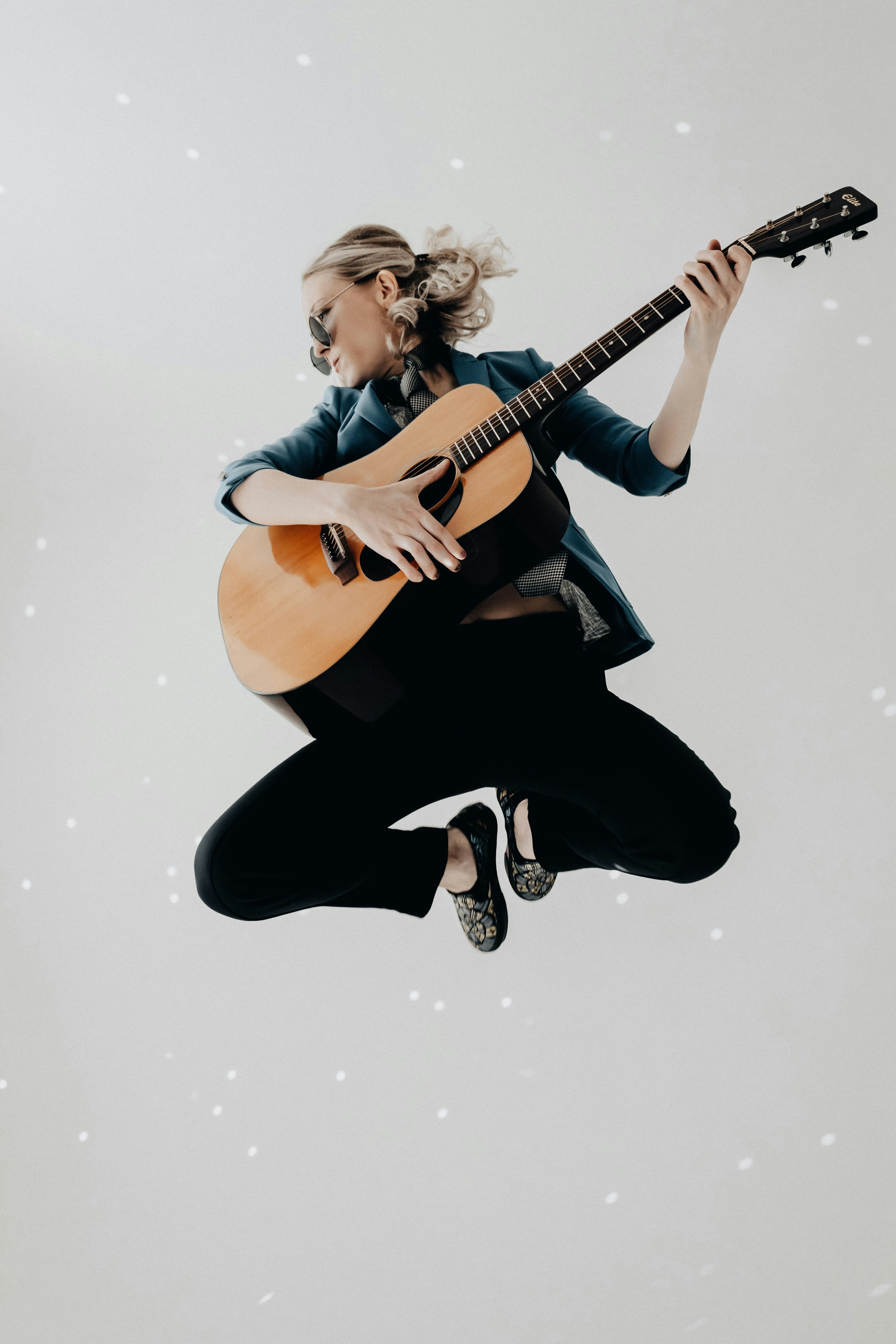 woman in black pants playing brown acoustic guitar